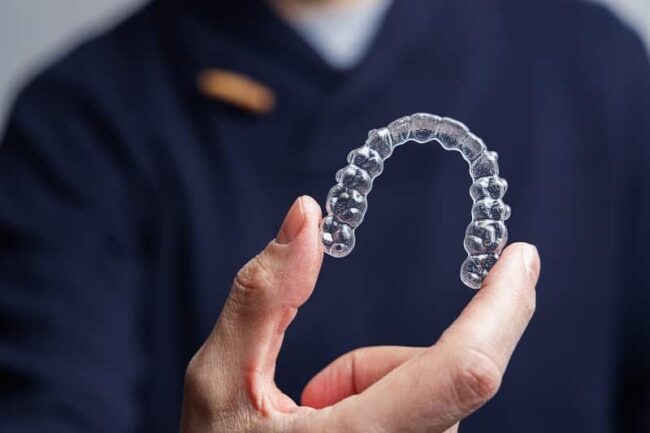 man holding Invisalign aligner