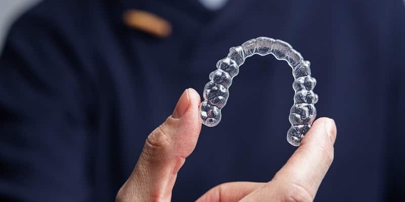 man holding Invisalign aligner
