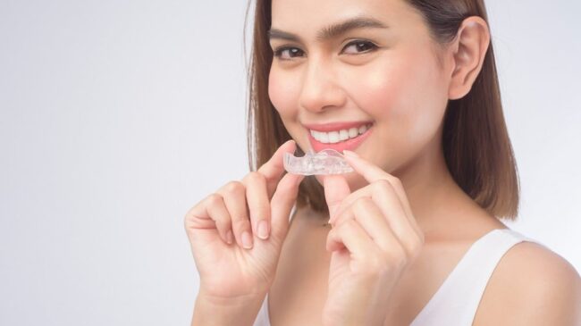 woman holding Invisalign clear braces